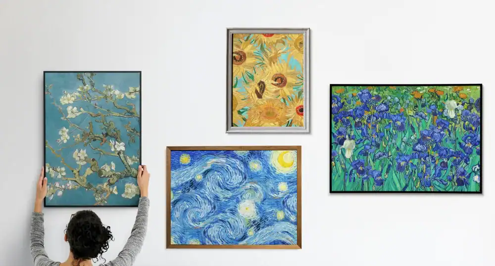 A person hangs a framed painting on a white wall alongside three other famous Vincent van Gogh artworks, including sunflowers, irises, and Starry Night.